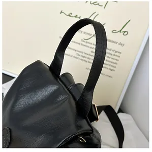 Detail eines schwarzen Kunstleder-Rucksacks mit Klappe, Tragegriff und feiner Textur