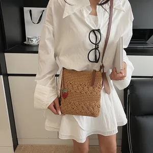 Brown woven crossbody bag with hollow flower patterns and cute strawberry charm details