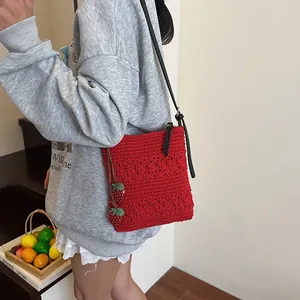 Red crochet crossbody bag with strawberry charms and black leather strap worn by model