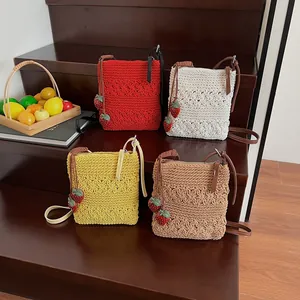 Handmade crochet crossbody bucket bags with strawberry charms in four vibrant colors