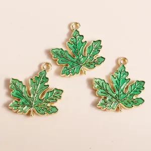 Detailed macro of three green enamel maple leaf charms with gold trim for DIY jewelry