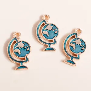 Trois pendentifs globe dorés avec émail bleu et anneaux de suspension sur fond beige