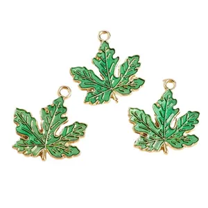 Three green and gold maple leaf charms for DIY jewelry making on white background