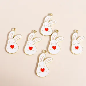 Detail of white enamel bunny charms with golden edges and red hearts for DIY jewelry