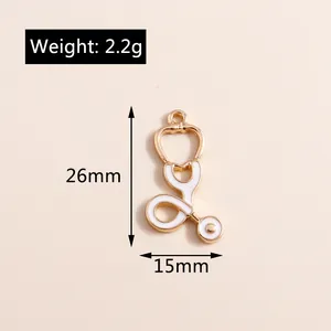Vue détaillée d'un pendentif stéthoscope doré de 26 mm avec émail blanc et mesures
