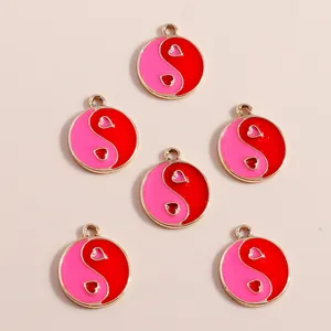 Macro shot of heart-shaped Yin Yang charms with pink and red enamel in gold finish