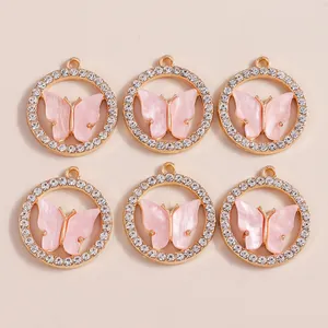 Nahaufnahme von rosa Emaille-Schmetterlingsanhängern mit Goldbasis und Strasssteinen