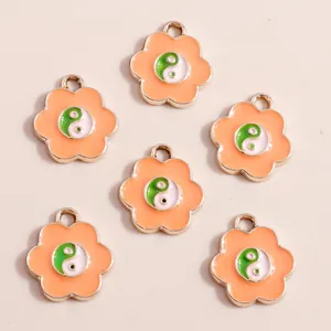 Detail view of flower-shaped alloy pendants with orange enamel and Yin Yang motifs