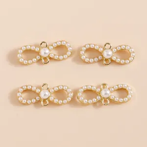 Macro detail of infinity bow charms with inlaid pearls and golden alloy base