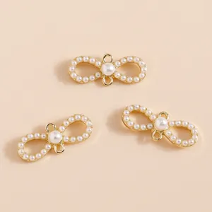 Three gold infinity charms with white pearls and dual hanging loops for DIY jewelry making