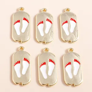 Detail of alloy paw print charms with white and red enamel on a light beige backdrop