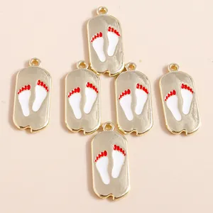Golden alloy dog paw print pendants with white enamel and red accents for DIY jewelry