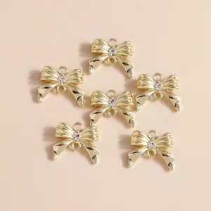 Primer plano de 6 colgantes de lazo dorado con diamantes para crear joyería personalizada
