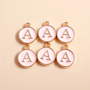 Detail of round letter A charms with pink enamel and gold-plated metal finish