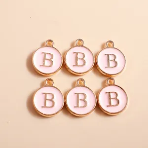 Detail of pink enamel and gold alloy letter B pendants for DIY jewelry making