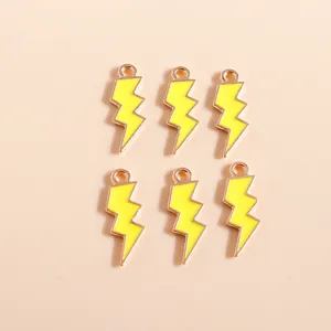 Detalle macro de seis colgantes de rayo en esmalte amarillo con bases de metal dorado DIY