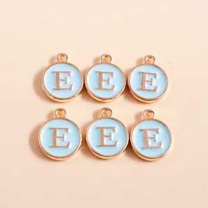 Close-up of circular light blue enamel letter E charms with golden alloy frame and loop