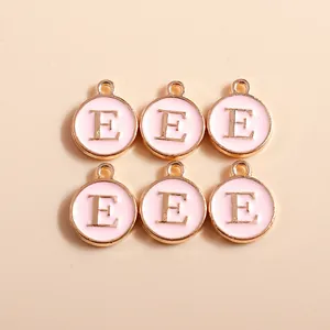 Detailed view of pink enamel and gold-plated letter E charms for DIY jewelry making