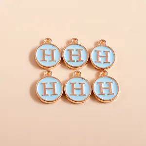 Detailed macro shot of light blue enamel letter H charms with gold metal plating