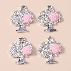 Nahaufnahme von silbernen Lebensbaum-Anhängern mit Strass und rosa Harzrosen