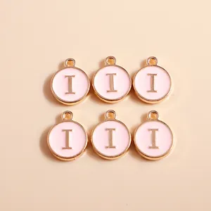 Macro shot of circular pink enamel DIY pendants with golden letter I for jewelry making