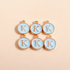 Close-up of light blue enamel letter K pendants with gold metal edge for DIY jewelry