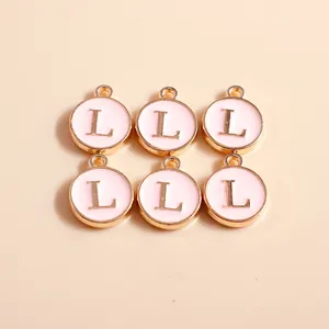 Detailed macro view of pink enamel and gold round letter L pendants with small hanging rings