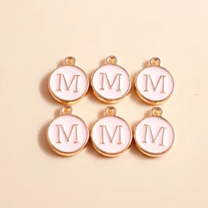 Detail of pink and gold enamel alphabet charms with embossed letter M for jewelry DIY