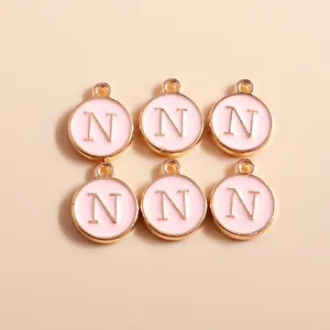 Detail of round pink enamel letter N pendants with gold plating for DIY jewelry