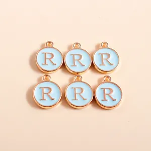 Close-up of circular light blue enamel letter R pendants with gold plating for DIY crafts