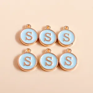 Close-up of six light blue enamel round charms with golden letter S for DIY jewelry making