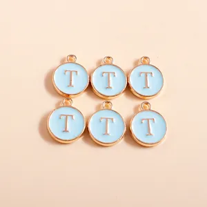 Close-up of six light blue enamel alphabet T charms with gold plated round alloy edges