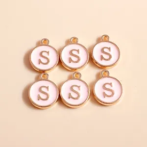 Detail view of pink enamel and gold alloy letter S pendants for DIY jewelry making