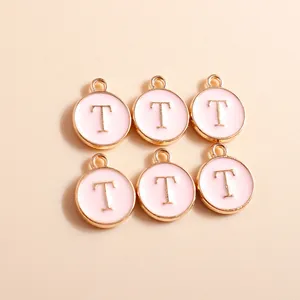 Close-up of pink enamel round letter T charms with gold plating for jewelry making