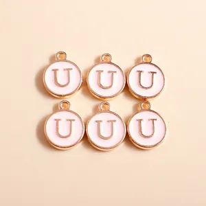 Macro view of six round pink enamel letter U charms with gold plating for jewelry making
