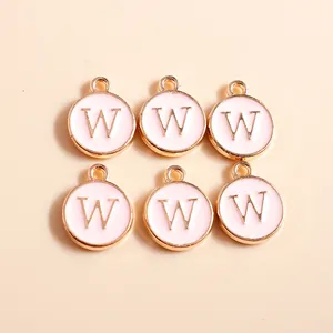 Detailed macro view of pink enamel letter W pendants with golden plating and top hanging loops