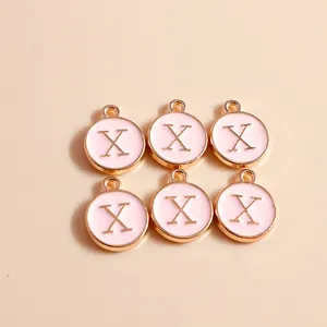 Detailed macro view of round pink enamel letter X charms with gold metal borders