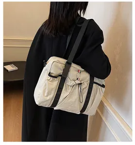 Detail der beigen Nylon-Tragetasche mit Kordelzugtaschen und Trikolore-Band an der Schulter