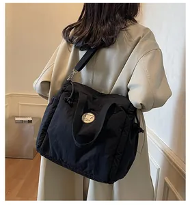 Modella che indossa una borsa tote in nylon nero con coulisse e dettaglio stemma fashion