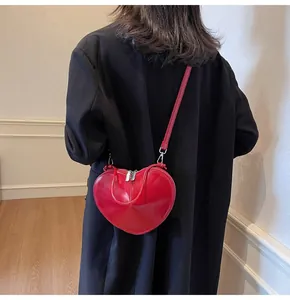 Detail of red heart-shaped crossbody bag with silver hardware on a black blazer