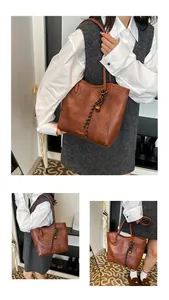 Detail of vintage brown tote bag with leather texture and decorative braided pendant