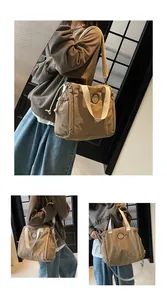 Dettagli di una borsa tote in tela kaki con logo orso e tracolla regolabile pratica