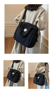 Dettaglio di borsa a tracolla in nylon trapuntato nero con coulisse e stemma moda
