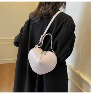 Detailed view of cream heart-shaped crossbody bag with glossy patent leather finish