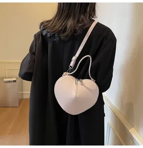 Detail of pink heart-shaped crossbody bag worn by a model in a black blazer