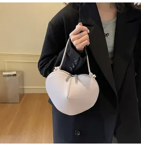 Macro view of light pink heart-shaped crossbody bag featuring double zipper details