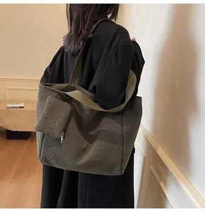 Detail of green houndstooth tote bag set with matching pouch on a model in a black suit