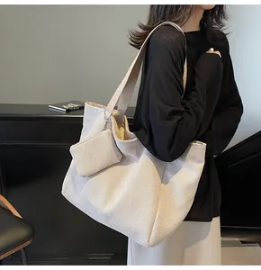 Detail of a large off-white woven tote bag with a small matching pouch and wide shoulder strap