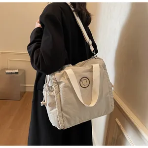 Dettaglio della borsa tote in nylon beige con stemma dell'orso e spalline larghe