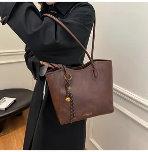 Detail of a dark brown leather tote bag with gold lettering and decorative pendant